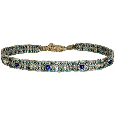 Esta pulsera está hecha a mano por nuestro equipo de artesanas usando hilos de poliester en tonos neutros, piedras semi-preciosas y bolitas de plata 925. Esta preciosa pulsera dará un toque chic a tu look por su estilo casual y su elegante colorido.  Detalles:      Bolitas de plata 925      Lapis lazuli      Hilos de poliéster      Hecho a mano      Cierre ajustable, que se adapta a cualquier tipo de muñeca.      Anchura 8 mm     Se puede mojar